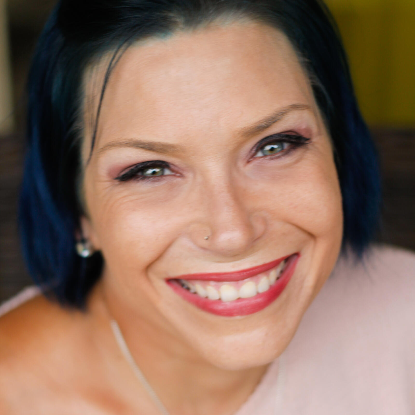 Headshot of woman smiling. She has blue hair. 