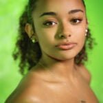 Gallery image of Black Model with curly Hair and in a green dress headshot.
