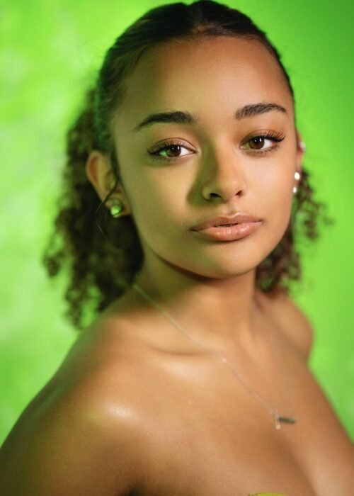 Black Model with curly Hair and in a green dress headshot.