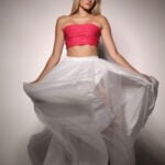 Gallery image of Blonde model in a pink tube top with white silky skirt