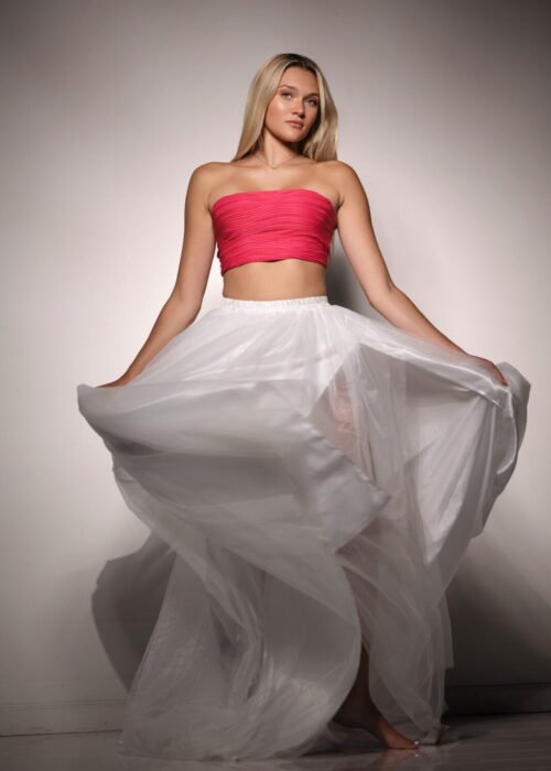 Blonde model in a pink tube top with white silky skirt