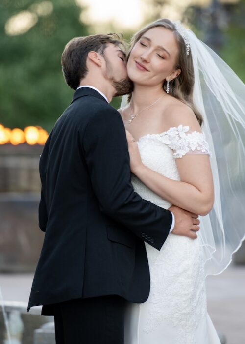 Beautiful image of wedding couple with romatic kiss and sunlit background